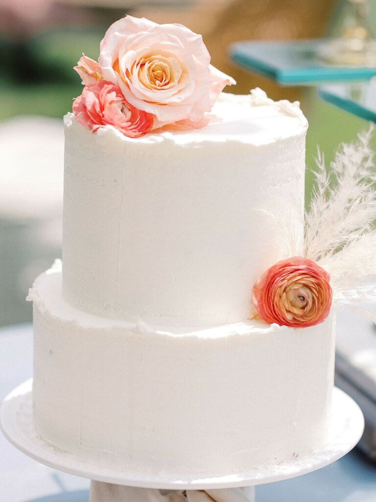 White two-tier wedding cake with fresh flowers
