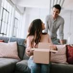 Woman opening up box on couch with partner