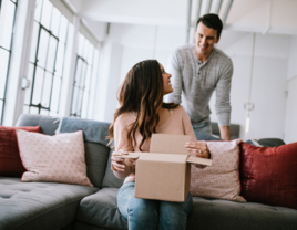 Woman opening up box on couch with partner