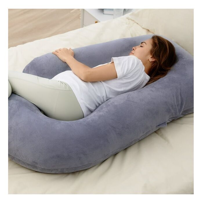 Woman laying on a pregnancy pillow in bed