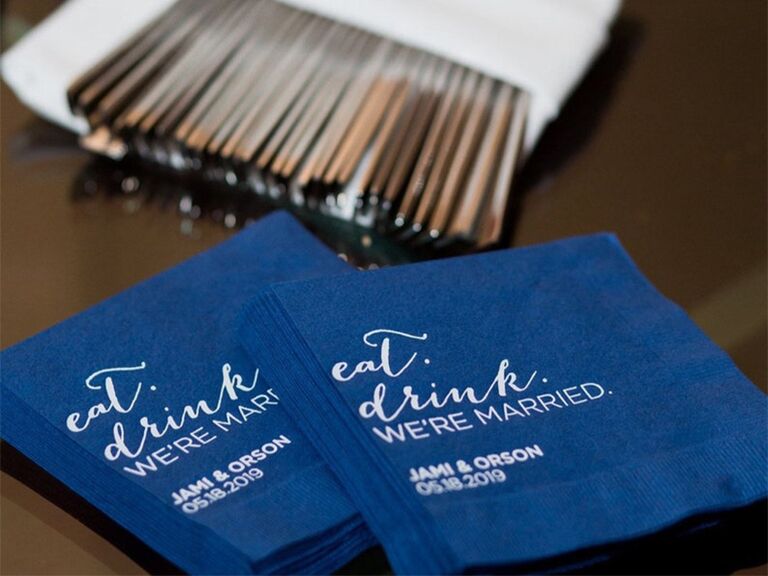Blue napkins with 'eat, drink, we're married' in white type above couple's names and date