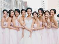 bride stands with bridesmaids wearing blush dresses