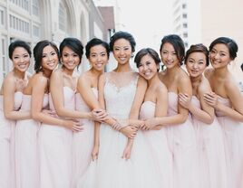 bride stands with bridesmaids wearing blush dresses