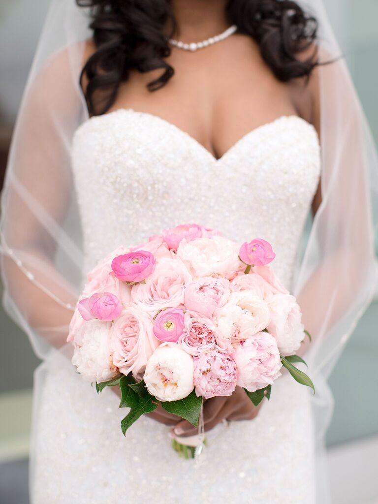 A bride holds a bouquet of ombré pink peonies.