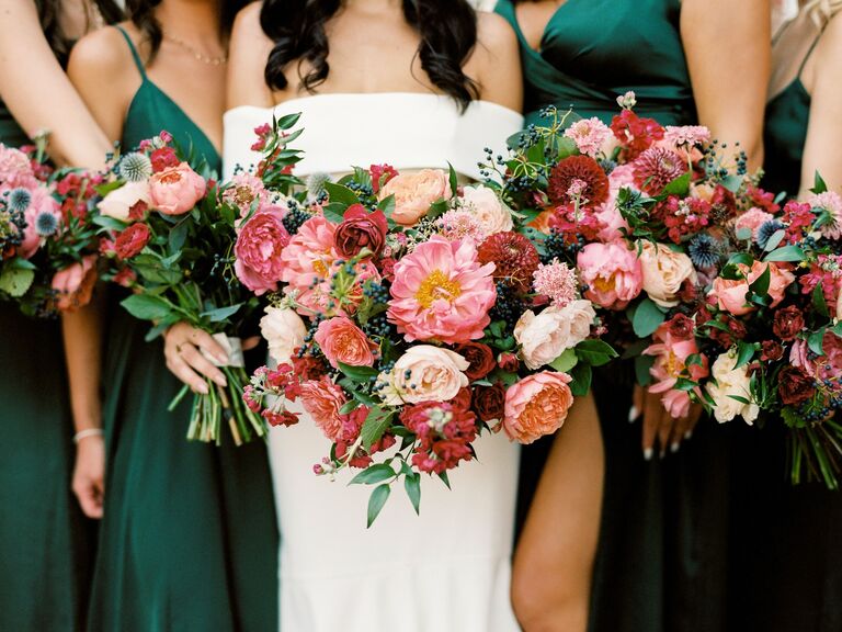 A bride and her bridesmaids hold jewel-toned peony bouquets.