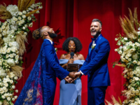 Grooms holding hands and laughing at altar