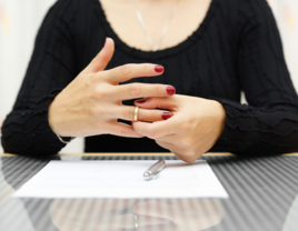 Woman taking off wedding ring while signing divorce papers