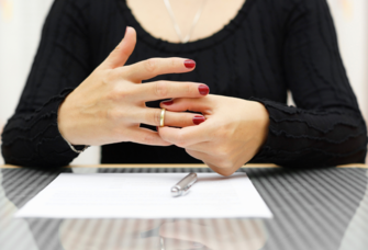 Woman taking off wedding ring while signing divorce papers