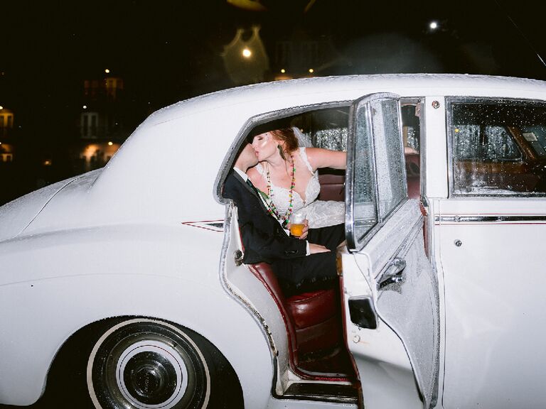 Direct flash wedding photography of couple kissing in getaway car