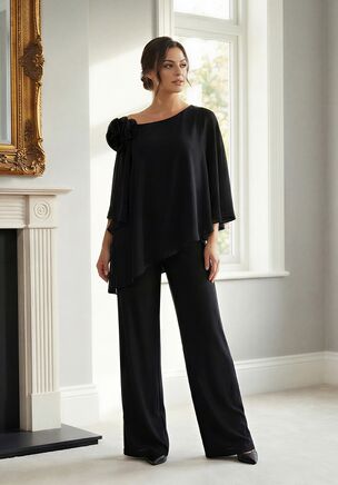 Fresh, chic, and full of confidence, this Stretch Soft Crepe two-piece pant suit is a stylish choice for the Mother of the Bride. The asymmetrical neckline and relaxed fit create an easy, flattering silhouette, while the angled top design adds movement and a fashion-forward edge. A statement flower at the shoulder brings a playful, refined touch, making this look feel youthful, polished, and perfectly on trend for a modern celebration.