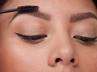 Person using a spoolie brush to comb their eyebrows