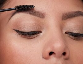 Person using a spoolie brush to comb their eyebrows