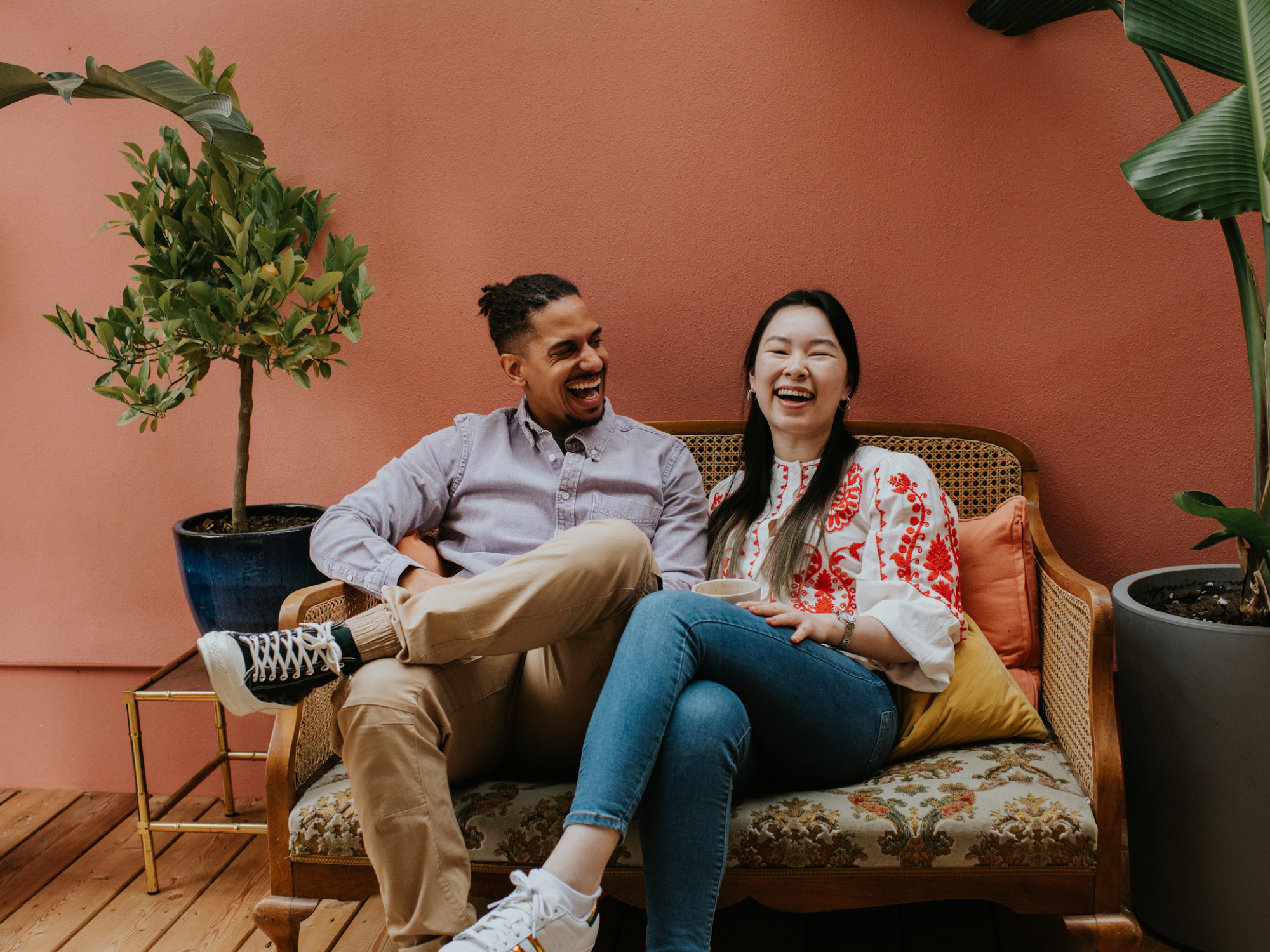 young couple sit on a sofa and laugh together