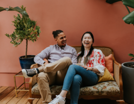 young couple sit on a sofa and laugh together