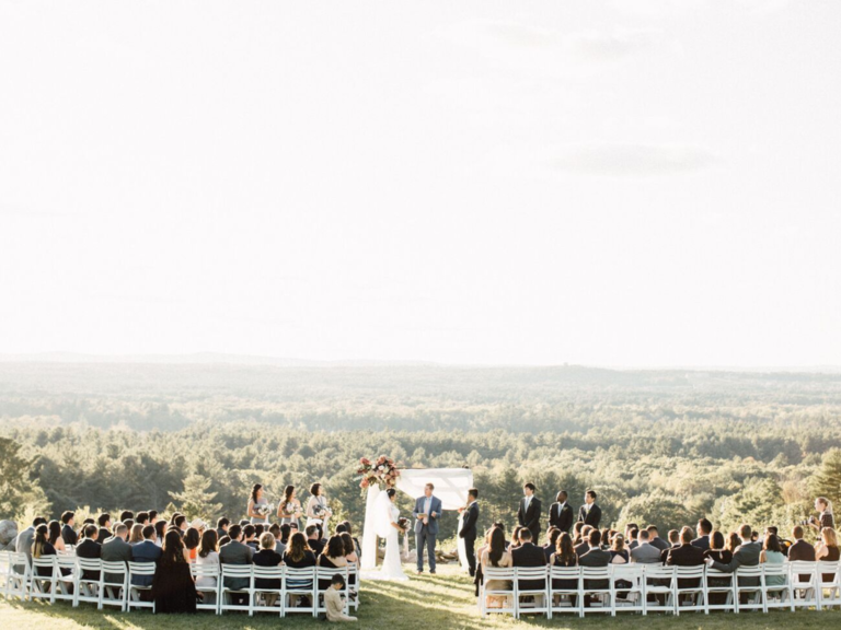 Outdoor wedding ceremony on edge of hill with view of forest