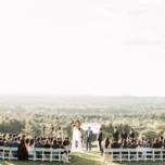 Outdoor wedding ceremony on edge of hill with view of forest