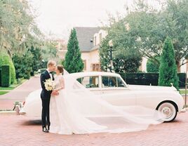 Couple kissing in front of vintage wedding car