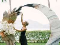 Wedding planner puts finishing touches on ceremony arch. 