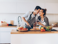 Couple cooking together in kitchen and laughing