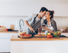 Couple cooking together in kitchen and laughing