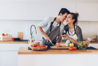 Couple cooking together in kitchen and laughing