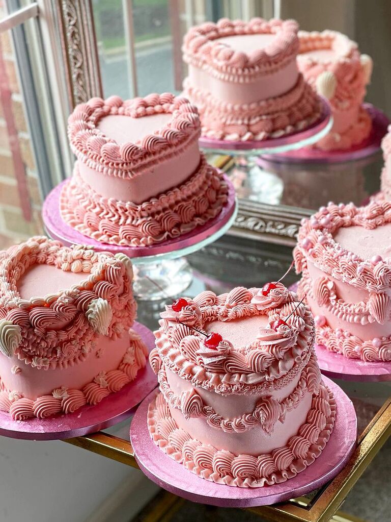 four heart shaped wedding cakes decorated with pink piping and cherries