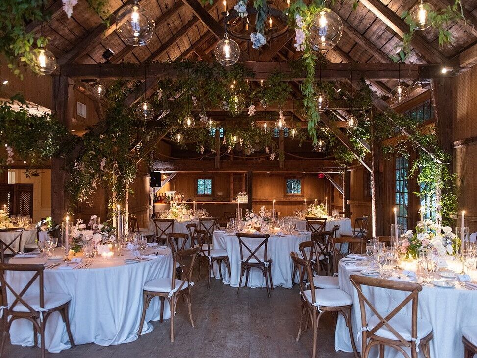 Inside beautiful barn venue with hanging foliage and light fixtures