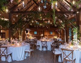 Inside beautiful barn venue with hanging foliage and light fixtures