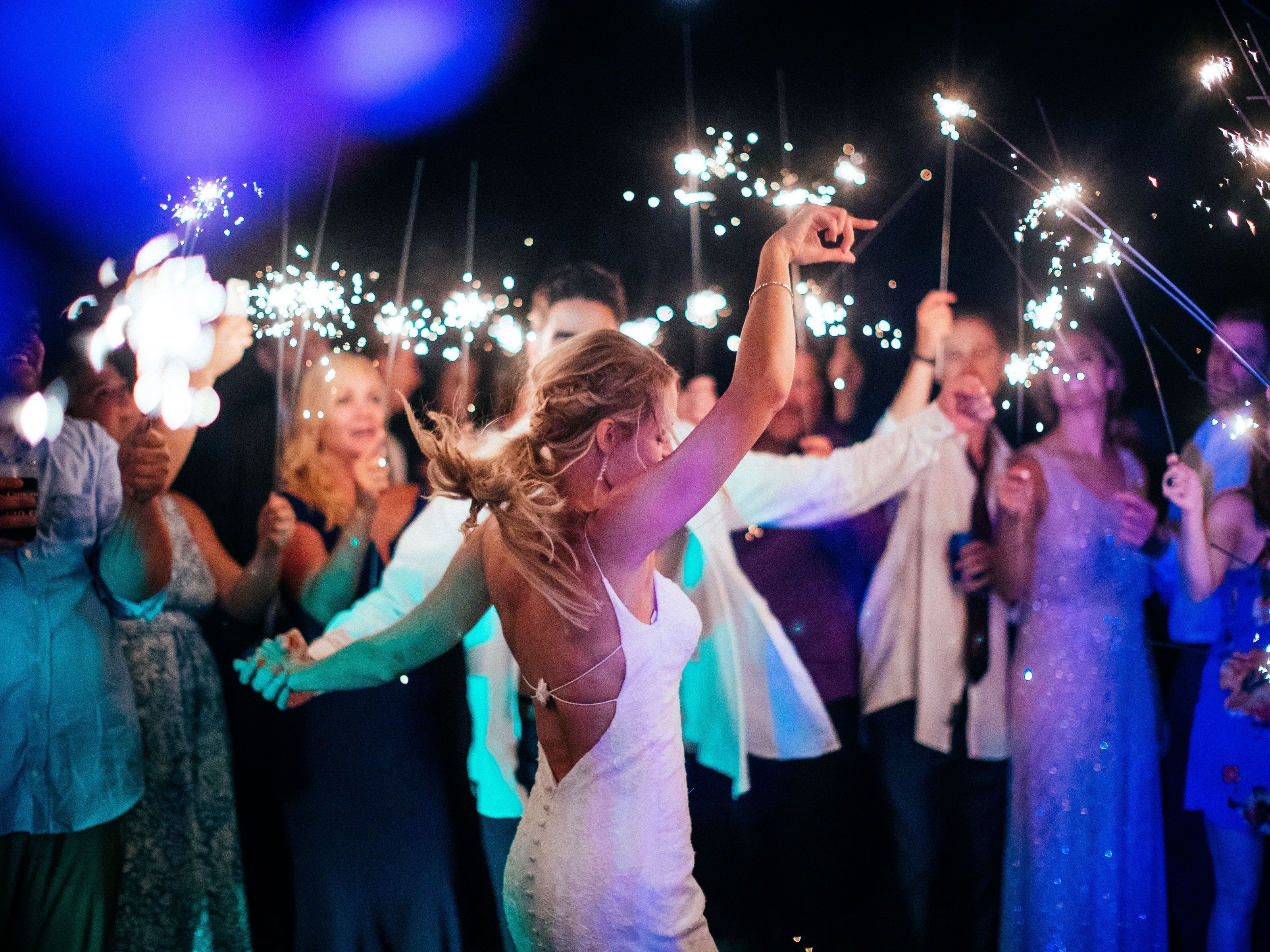 Bride and groom dancing while guests celebrate with sparklers