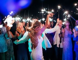 Bride and groom dancing while guests celebrate with sparklers