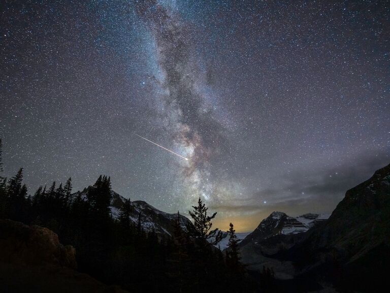 A night sky with the Milky way and shooting star over mountains at Peyto Lake, Banff national park, Alberta, Canada