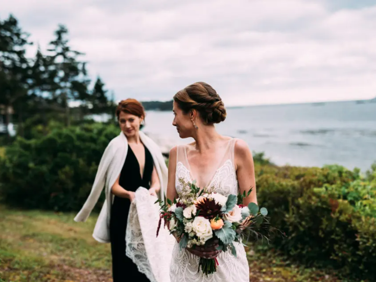 Bride with friend carrying her dress on 