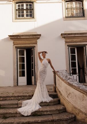 Cava Dress a captivating mermaid silhouette crafted from luxurious shimmering lace. This gown features a striking open back that exudes elegance and allure. It fastens with a hidden zipper at the back and delicate buttons at the neck, creating a seamless and graceful finish. Perfect for brides who want to make a sophisticated statement with every step.