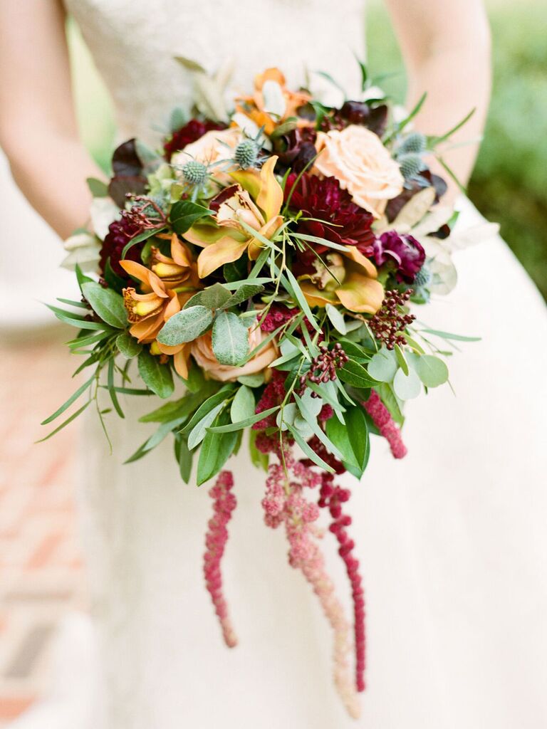 Bride holding fall wedding bouquet with rusty yellow and burgundy flowers