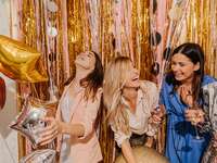Group of women laughing in front of backdrop at bridal shower