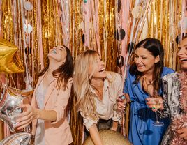 Group of women laughing in front of backdrop at bridal shower
