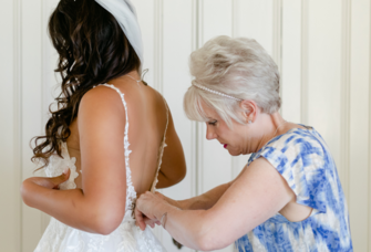 Mother in law helping bride with her wedding dress