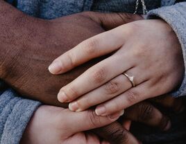 Woman wearing engagement ring holding hands with partner