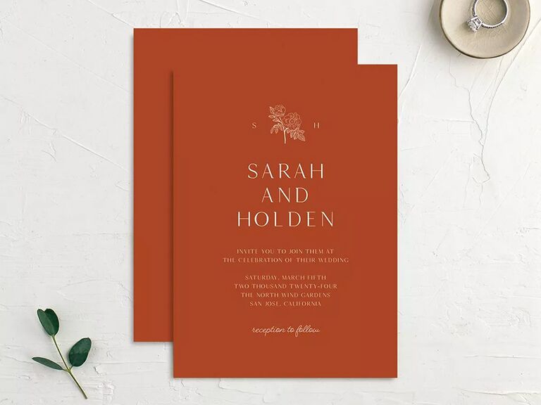 Monogram and floral graphic above names and event details in minimal white type on burnt orange background