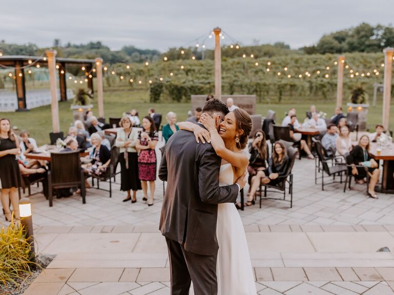 Couple enjoying a slow dance outside surrounded by loved ones