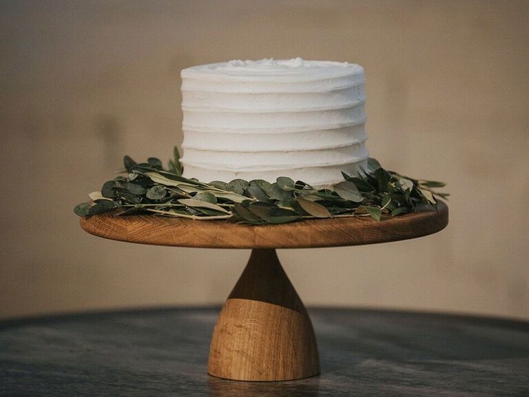 Single-tier rustic cutting cake with white icing and eucalyptus leaves
