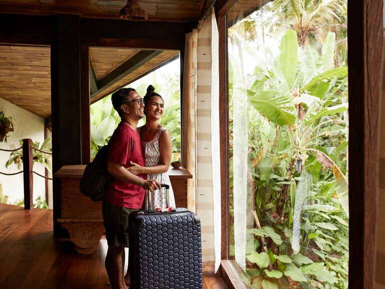 Happy couple standing near window at villa in Bali