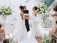 Brides at altar during ceremony with officiant.