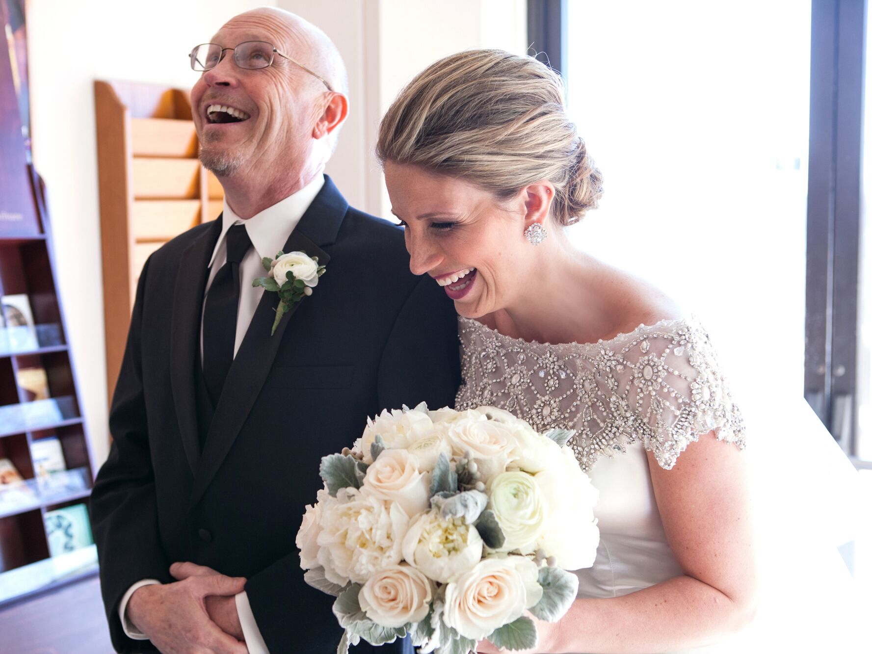A bride and her father laughing just before the wedding ceremony