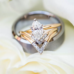 Diamond engagement ring sitting atop a silver wedding band.