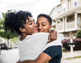 Lesbian couple embracing in front of home