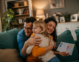 Mom and dad hugging their daughter after receiving mother's day card