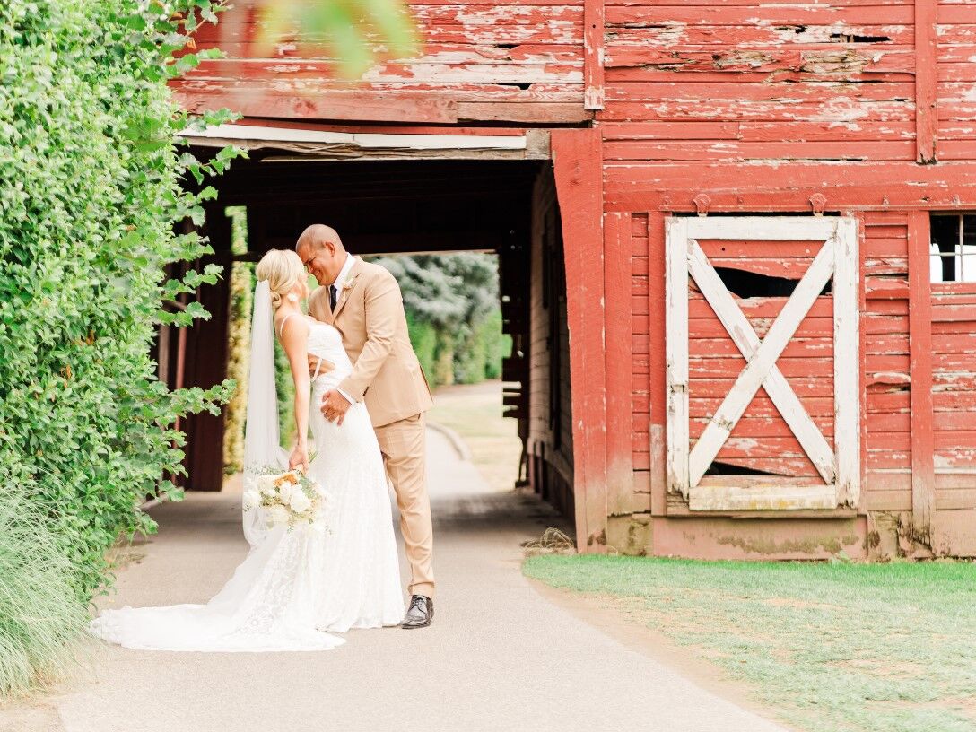 Couple posing for a portrait beside an old red barn