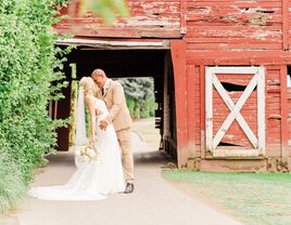 Couple posing for a portrait beside an old red barn