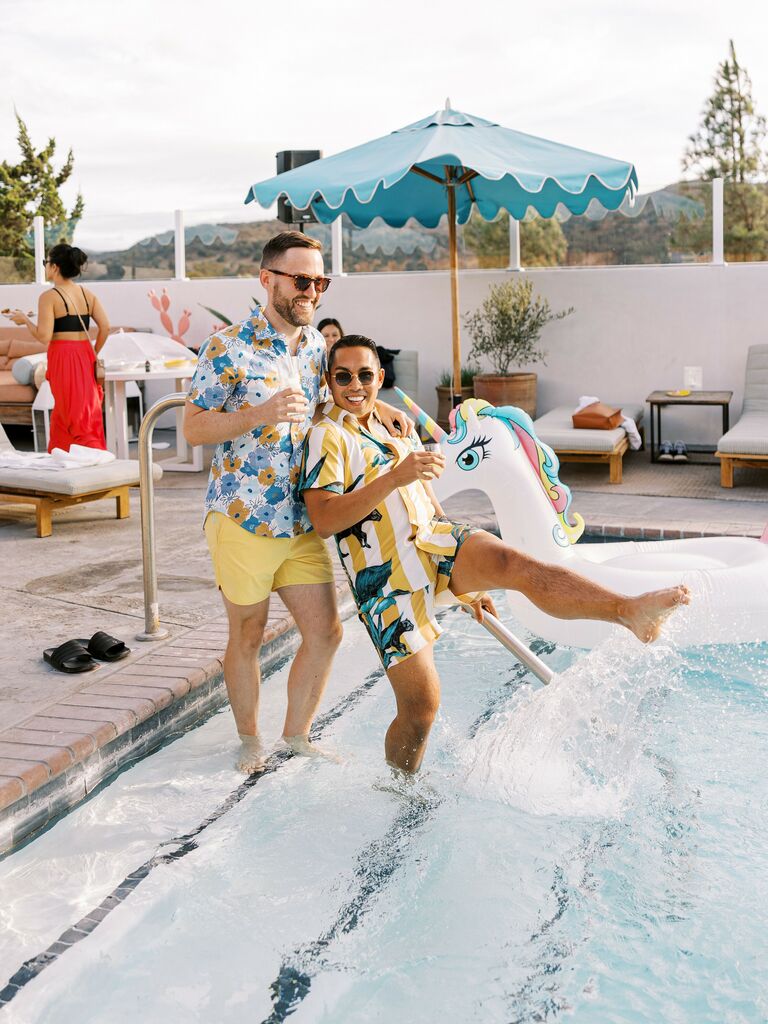 Couple splashes in the pool while smiling at the camera. 